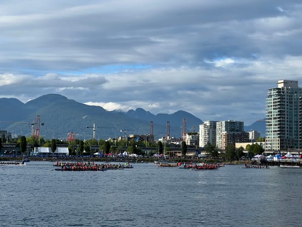 Picture of Vancouver landscape with water in the forefront with dragon boats and mountains and buildings in the background